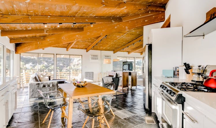 A giant open loft, with a dining table, kitchen, and living room visible, with floor to ceiling wind...