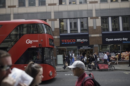 A red double-decker bus drives past a Tesco Plc Metro store London, U.K., on Tuesday, Aug. 6, 2019. 
