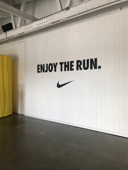 A white gym wall with Nike's sign and 'Enjoy the run.' written on it