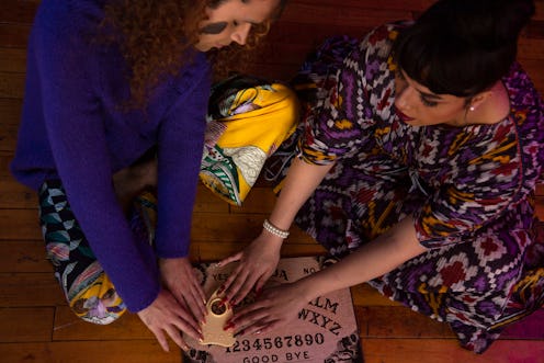 Two people use a Ouija board. For trans and nonbinary folks, Halloween can be a valuable time to pla...