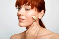A woman using a silegend Jade Roller on her cheek