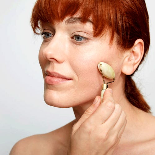 A woman using a silegend Jade Roller on her cheek