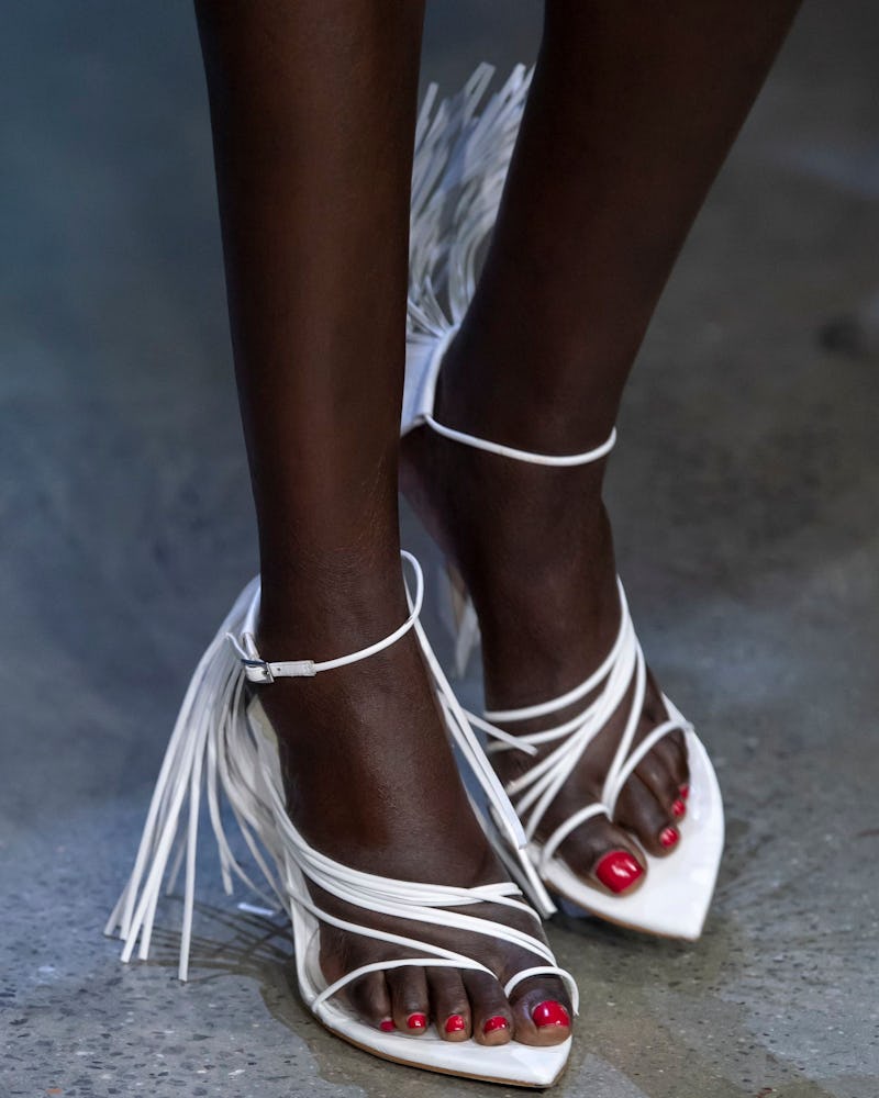 A woman wearing white sandals with fringe as on of the 7 Spring/Summer runway shoe trends