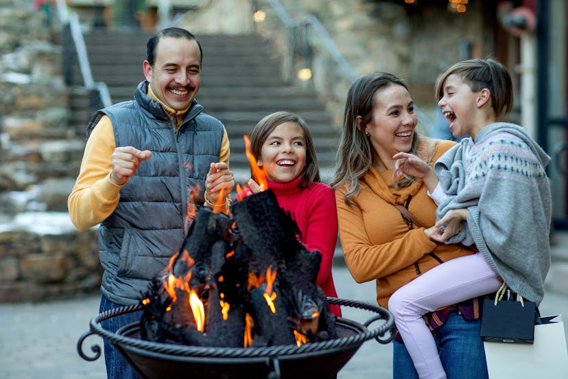 Mom, dad, and two children stand around fireplace.