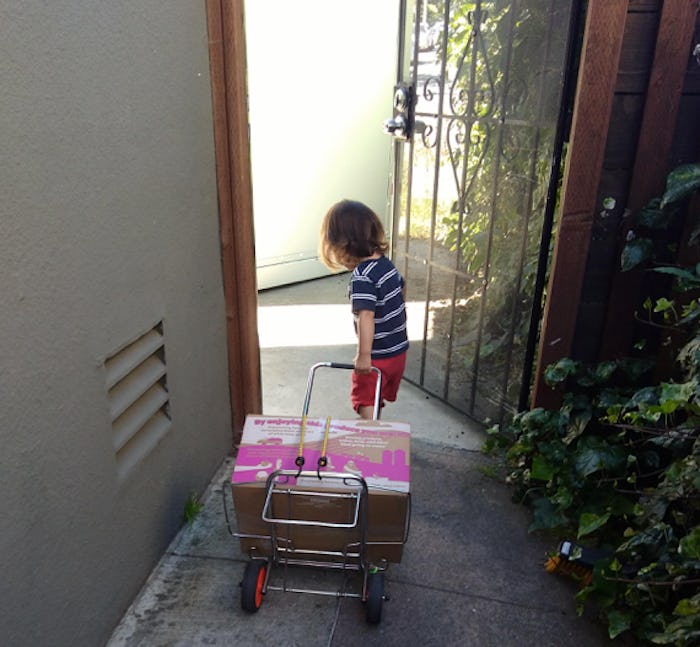 A picture of a young child pulling a cart behind them as they exit their home. 