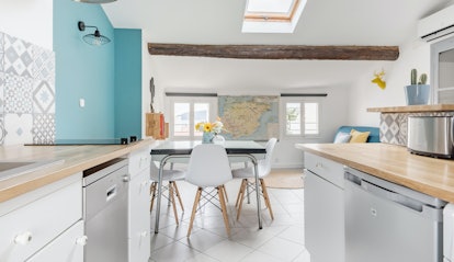 A comfortable apartment in Toulon has a bright kitchen with a single blue wall and wood details.
