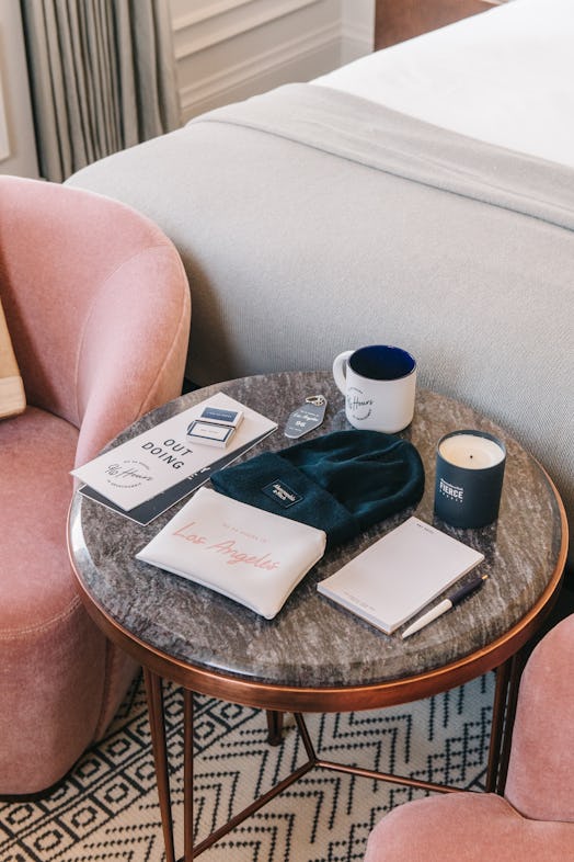 A dark marble coffee table with staycation products — like an itinerary, beanie, candle, toiletry po...