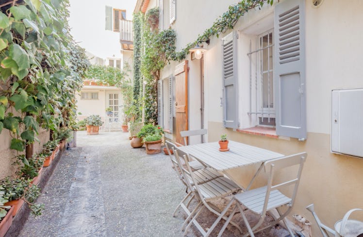 The entrance to a townhouse in Antibes is decorated with a table and chairs and lots of greenery.