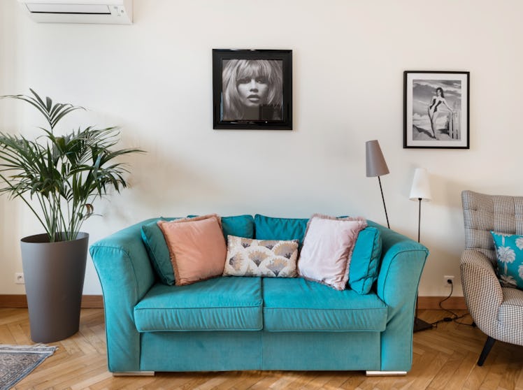 The living room of an apartment in Nice has a bright blue couch with pillows and stylish artwork.