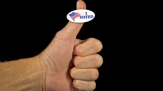 A thumb up in front of a black background and 'I voted' sticker on it