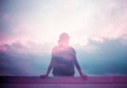 A depressed person sitting on a wall with a cloud overlay.