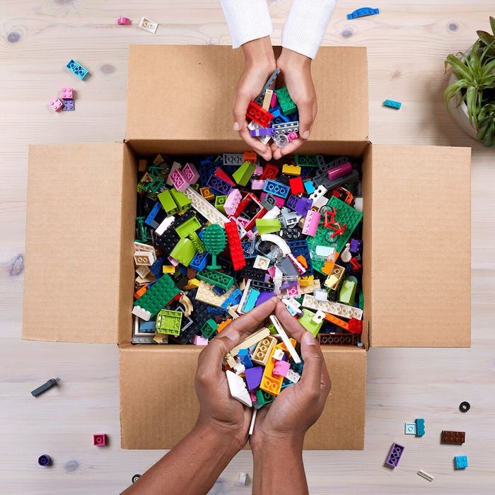 box of LEGO pieces, hands holding assorted LEGO bricks