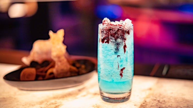 This blue Instagrammable Disney drink has black cherry purée that drips down the ice.