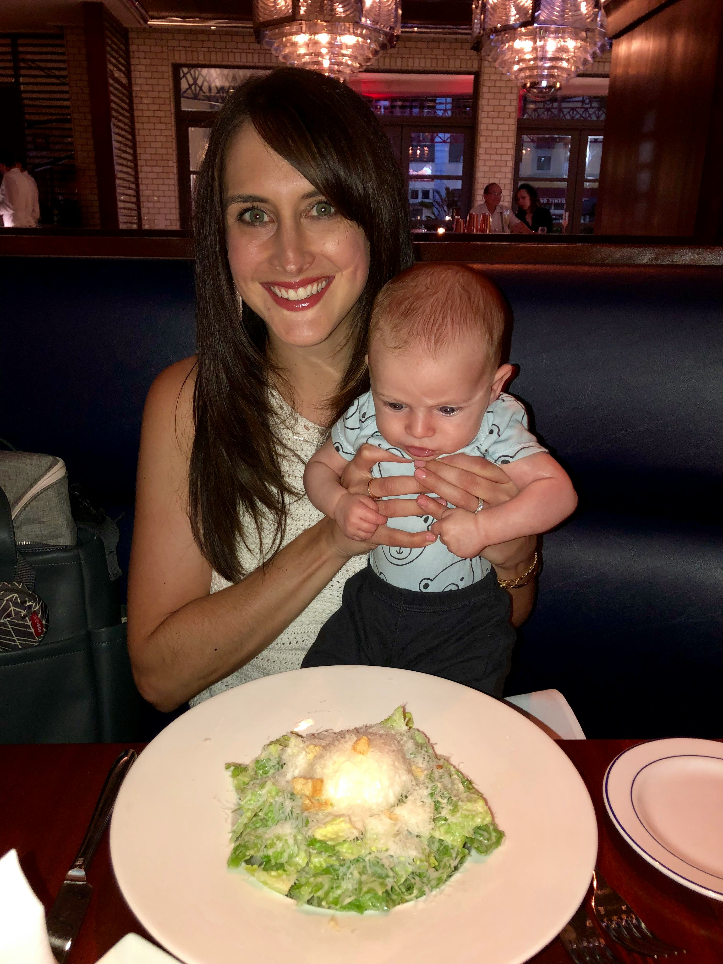 mom holds baby up in air with arms around baby's waist