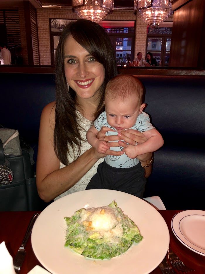 mom holds baby up in air with arms around baby's waist