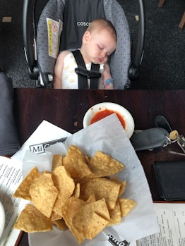 Baby sleeping in car seat next to a restaurant table. 