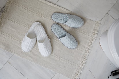 Two pairs of cozy slippers on a tile floor with a rug is something you may experience in the Allswel...