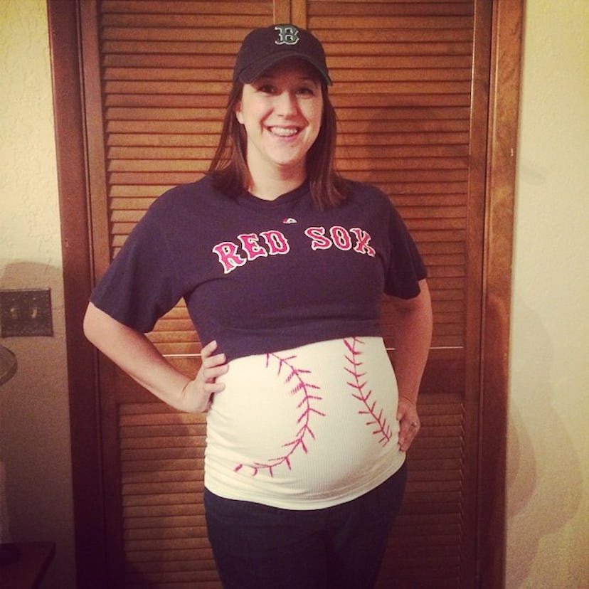 A pregnant woman wearing a Boston Red Sox t-shirt with a baseball printed on her belly
