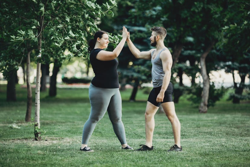 Two people high five each other after working out on a grassy field. Remember that only you can dete...