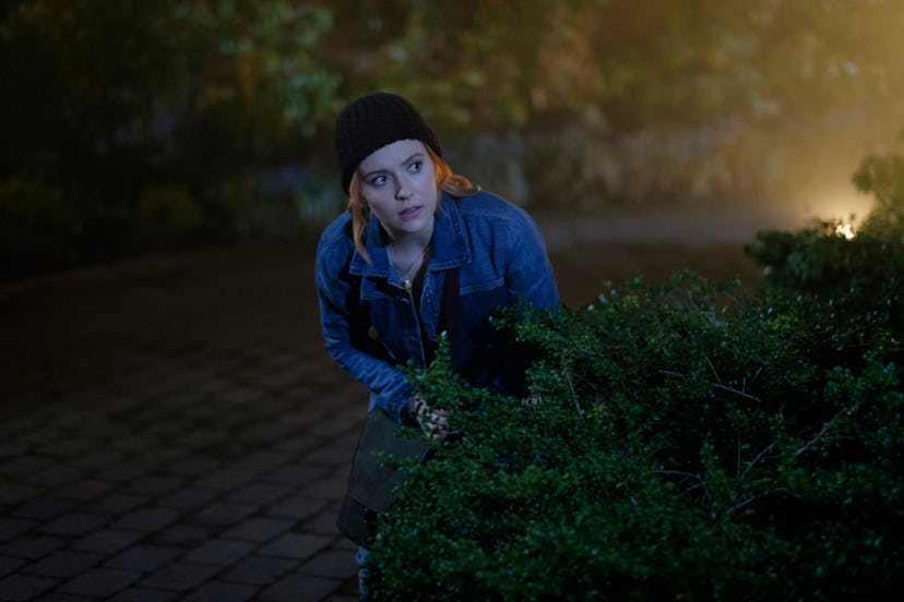 Kennedy McMann as Nancy Drew lurks behind a bush about to break in a house in the CW's Nancy Drew 