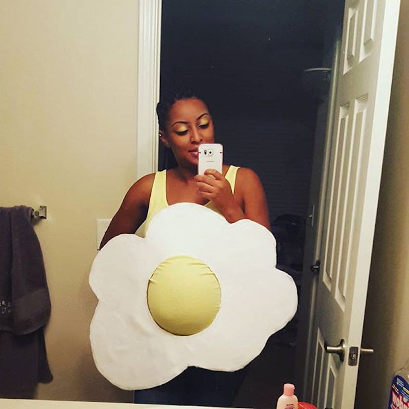 A pregnant woman taking a mirror selfie wearing a Sunny Side Up Egg clever maternity costume.