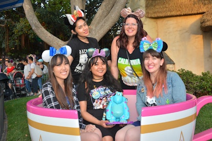 A group of women sit in a pink tea cup like the ride at Disneyland. 