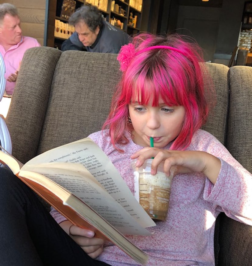 Girl sips drink while reading book
