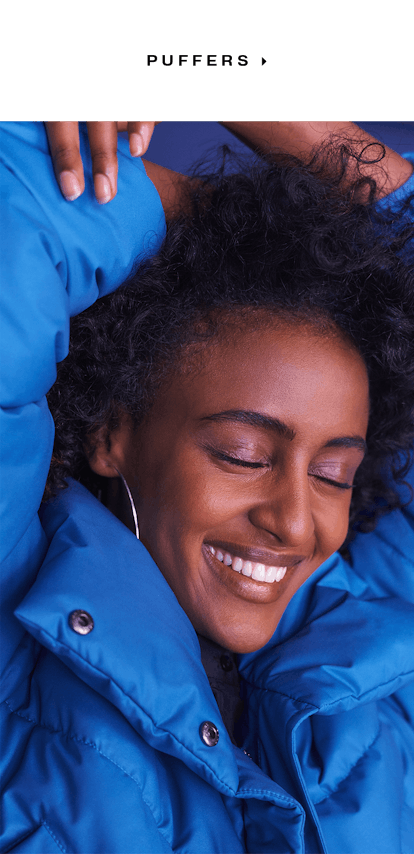 A woman in a blue hoodie smiling with her eyes closed