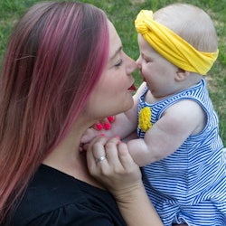 Mother with pink hair kisses baby