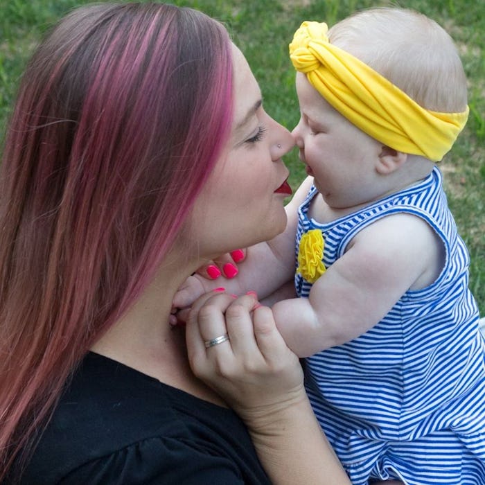 Mother with pink hair kisses baby