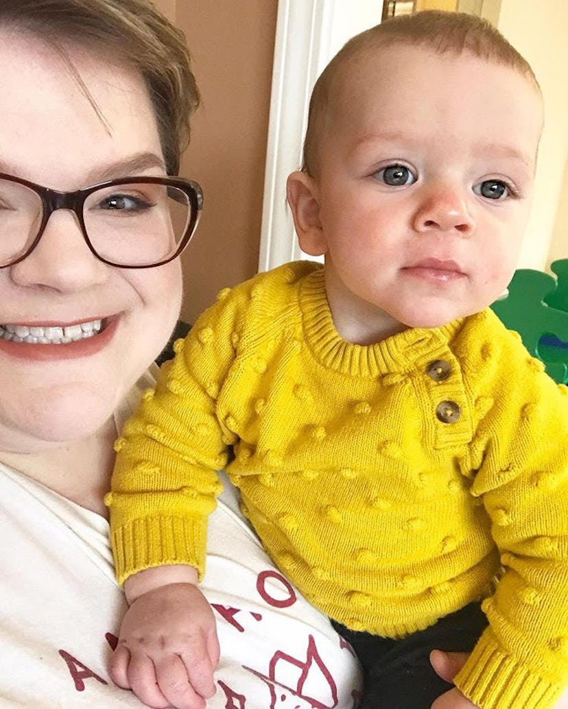 A mother holding up her toddler, wearing a bright yellow top.