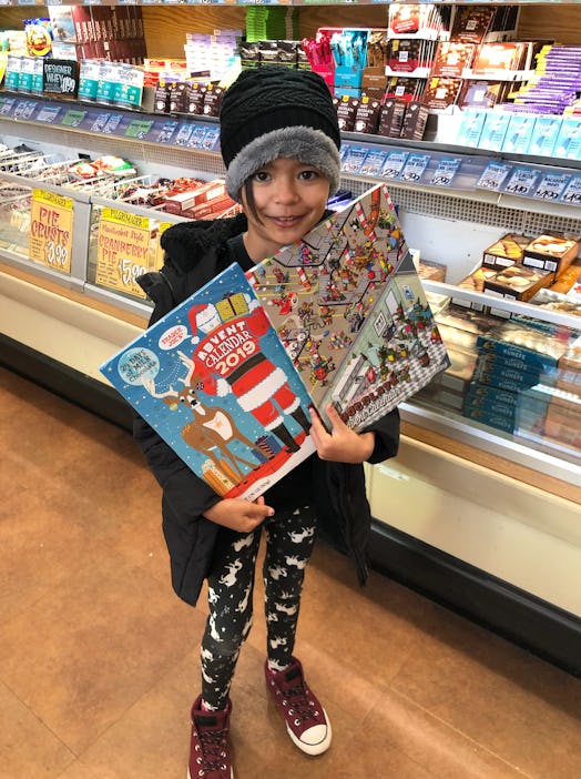 The author's daughter holds up two Trader Joe's advent calendars, including one for pets.