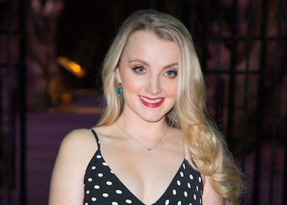 Evanna Lynch, with her long blonde hair, wearing a black dress with white polka dots, and smiling.