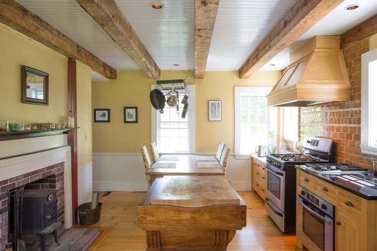 The kitchen of a 1780 farm house in Kennebunkport, Maine has a wooden table and indoor fireplace.