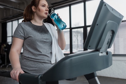 A person cools down from a treadmill workout with a blue water bottle. Make sure you're warmed up be...