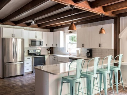 The kitchen of a house in Kennebunkport, Maine has teal chairs and a charming, rustic style.