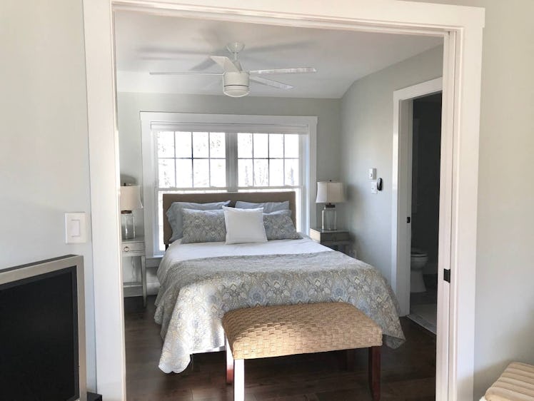 The bedroom of a studio apartment in Kennebunk is decorated with neutral bedding and cozy lighting.