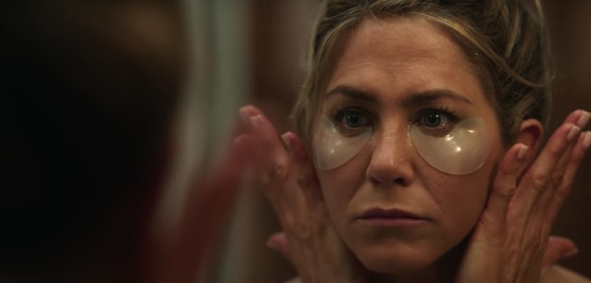 A close-up of Alex Levy looking at herself in the mirror wearing undereye patches. 