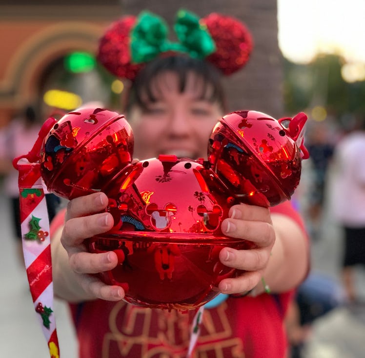 A woman holds a shiny red Mickey Jingle Bell Sipper that's available at Disney for the holidays out ...