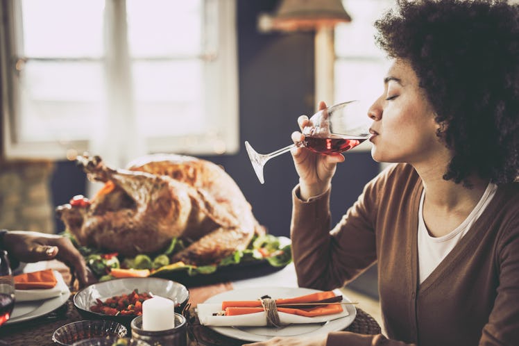 Woman eating Thanksgiving dinner, drinking wine.