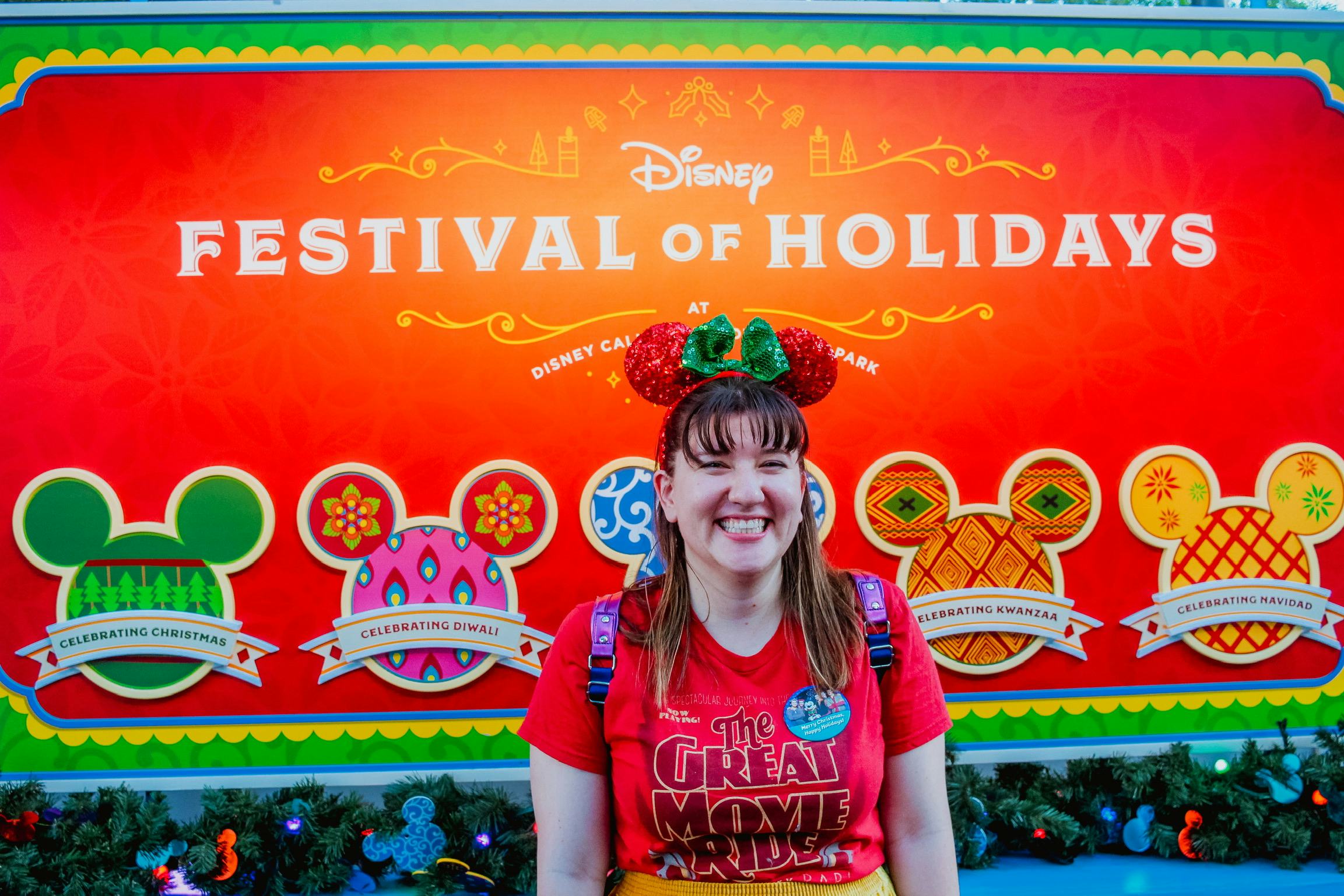 Woman wearing Minnie Ears standing in front of the Festival of Holidays sign at Disney's California ...