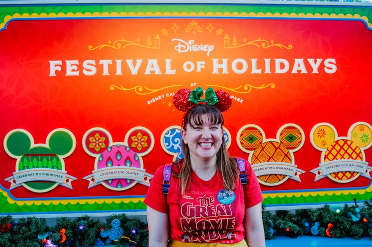 Woman wearing Minnie Ears standing in front of the Festival of Holidays sign at Disney's California ...