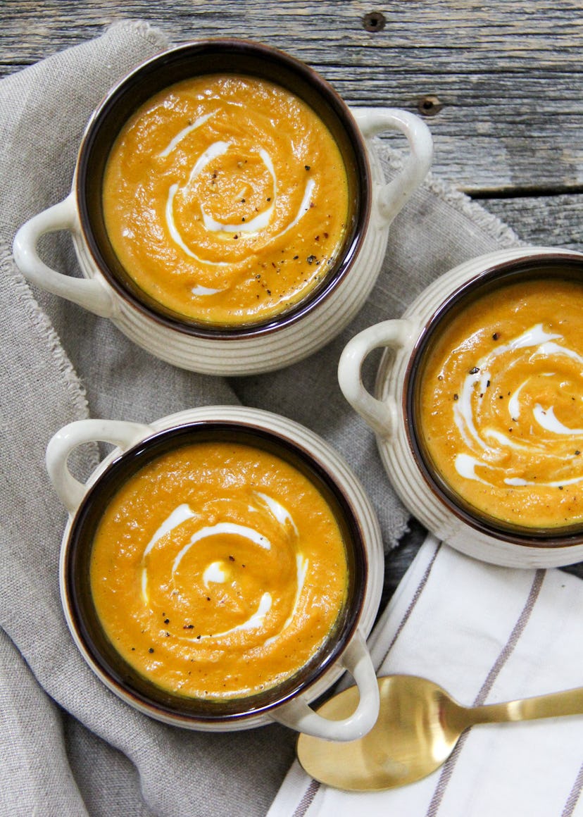 Easy Thanksgiving dishes; Pumpkin Soup served in three bowls with a gold spoon sitting next to them
