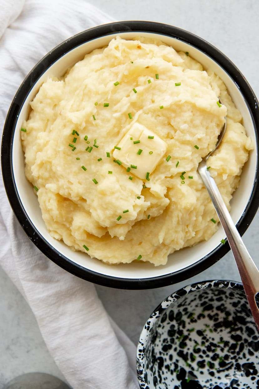 Easy Thanksgiving Dishes; bowl of crock pot mashed potatoes with chives and a square of butter