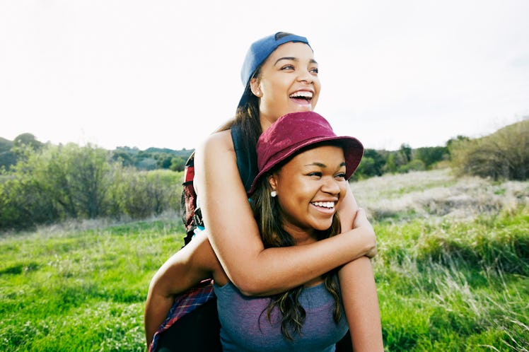 Protective older sister giving younger sister piggyback ride
