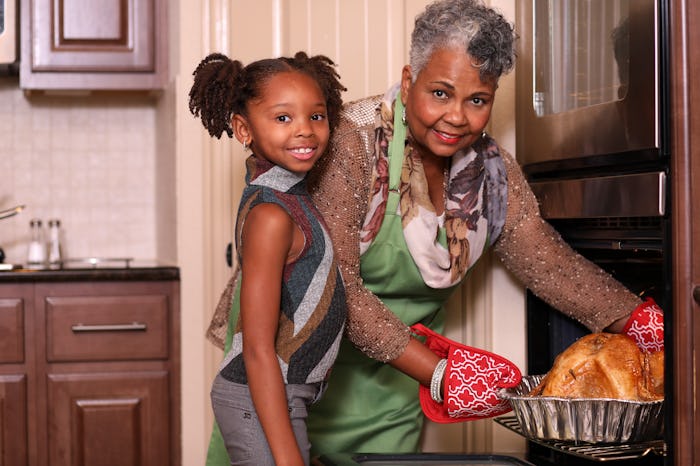 Mom puts turkey in oven for Thanksgiving while little girl helps