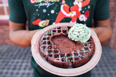 A man holds a plate with the Santa Mickey Waffle sundae on it, which is available only at Mickey's V...