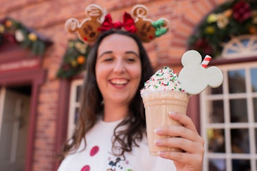 A woman holds a Christmas Cookie Shake in her hand at Mickey's Very Merry Christmas Party.