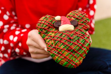 A woman holds the a holiday-themed Mickey cinnamon roll that's available at Mickey's Very Merry Chri...