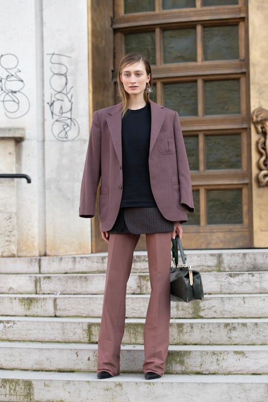 Street style photo of model Felize Kolibius wearing a layered look with a maroon blazer, black sweat...